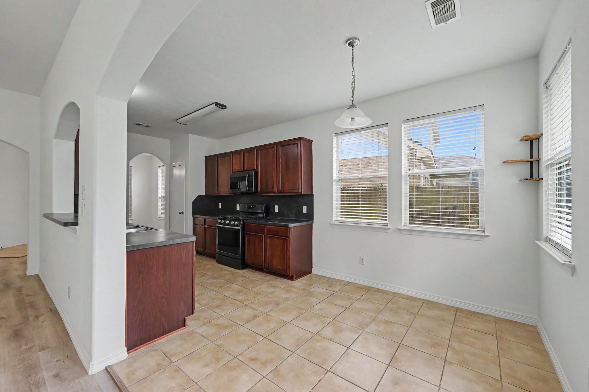 13035 Avery Ridge Lane Tomball, TX 77377 - Photo 9 of 27 The kitchen features rich dark wood cabinetry, sleek black appliances, and a bright, airy breakfast room with large windows.