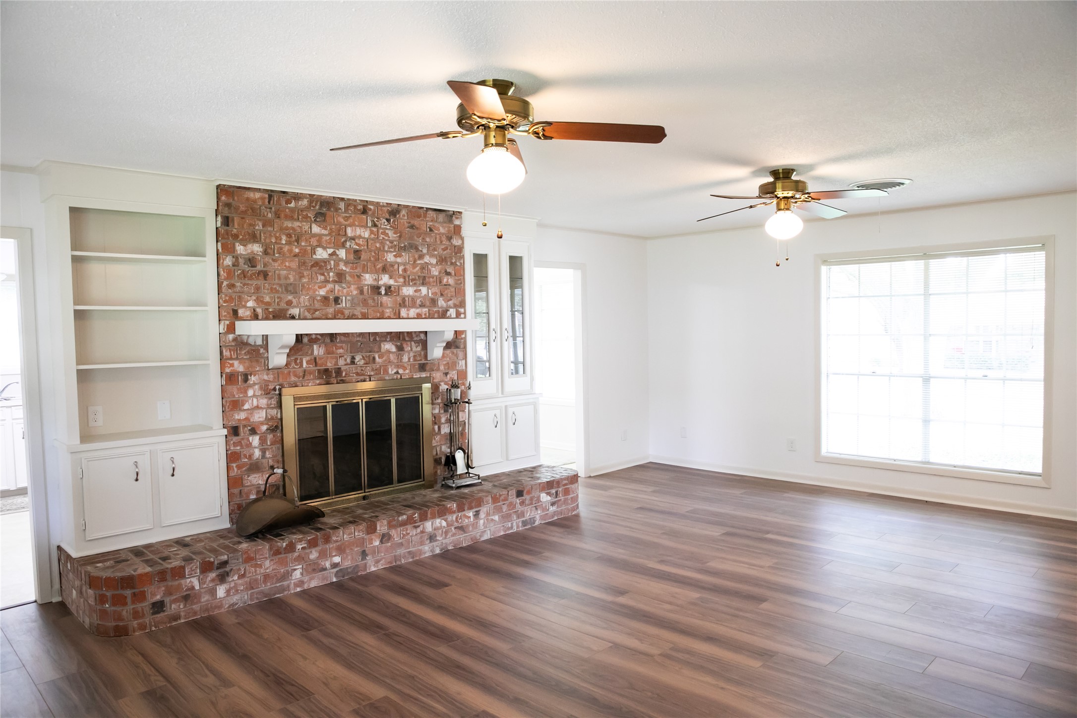 1600 Reimer Street Brenham, TX 77833 - Photo 11 of 24 an empty room with windows fireplace and a ceiling fan