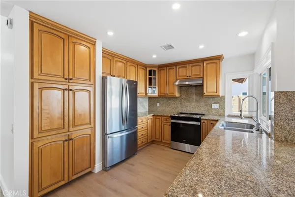 a kitchen with granite countertop stainless steel appliances a refrigerator cabinets and wooden floor
