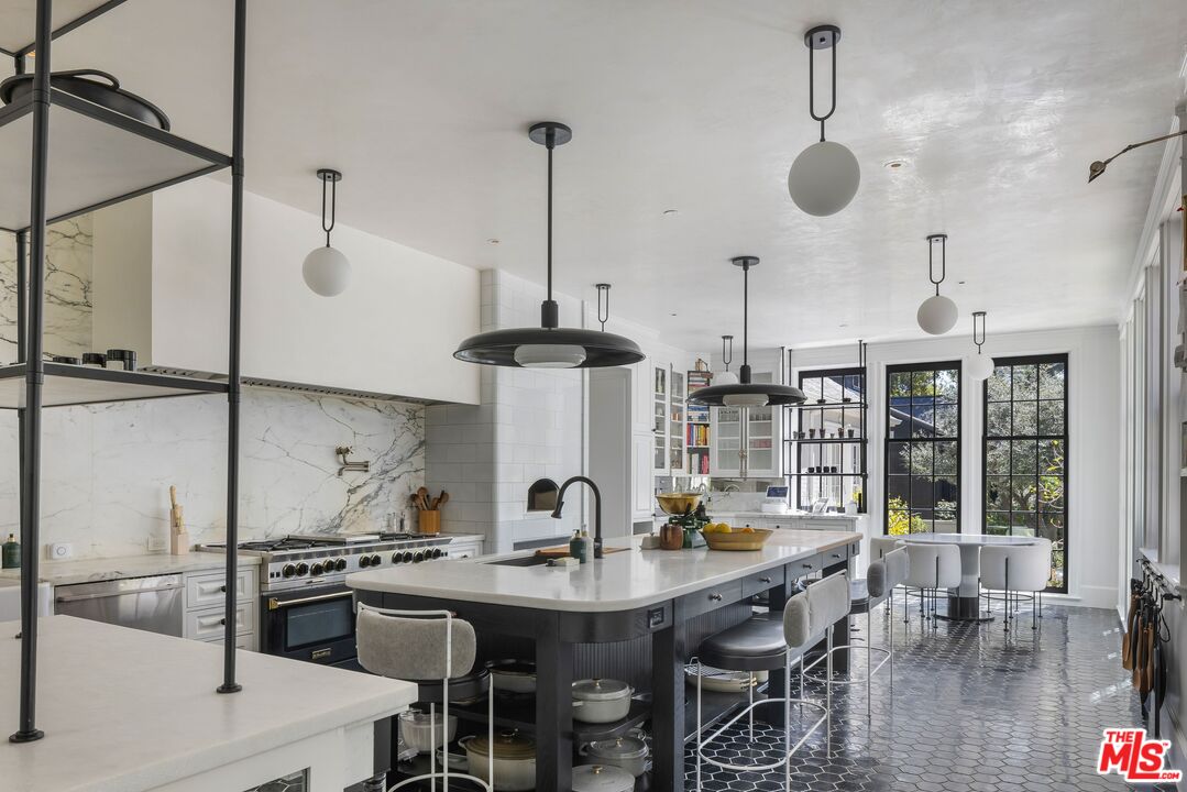 1701 Westridge Road Los Angeles, CA 90049 - Photo 13 of 36 a kitchen with stainless steel appliances granite countertop a sink a stove and chairs
