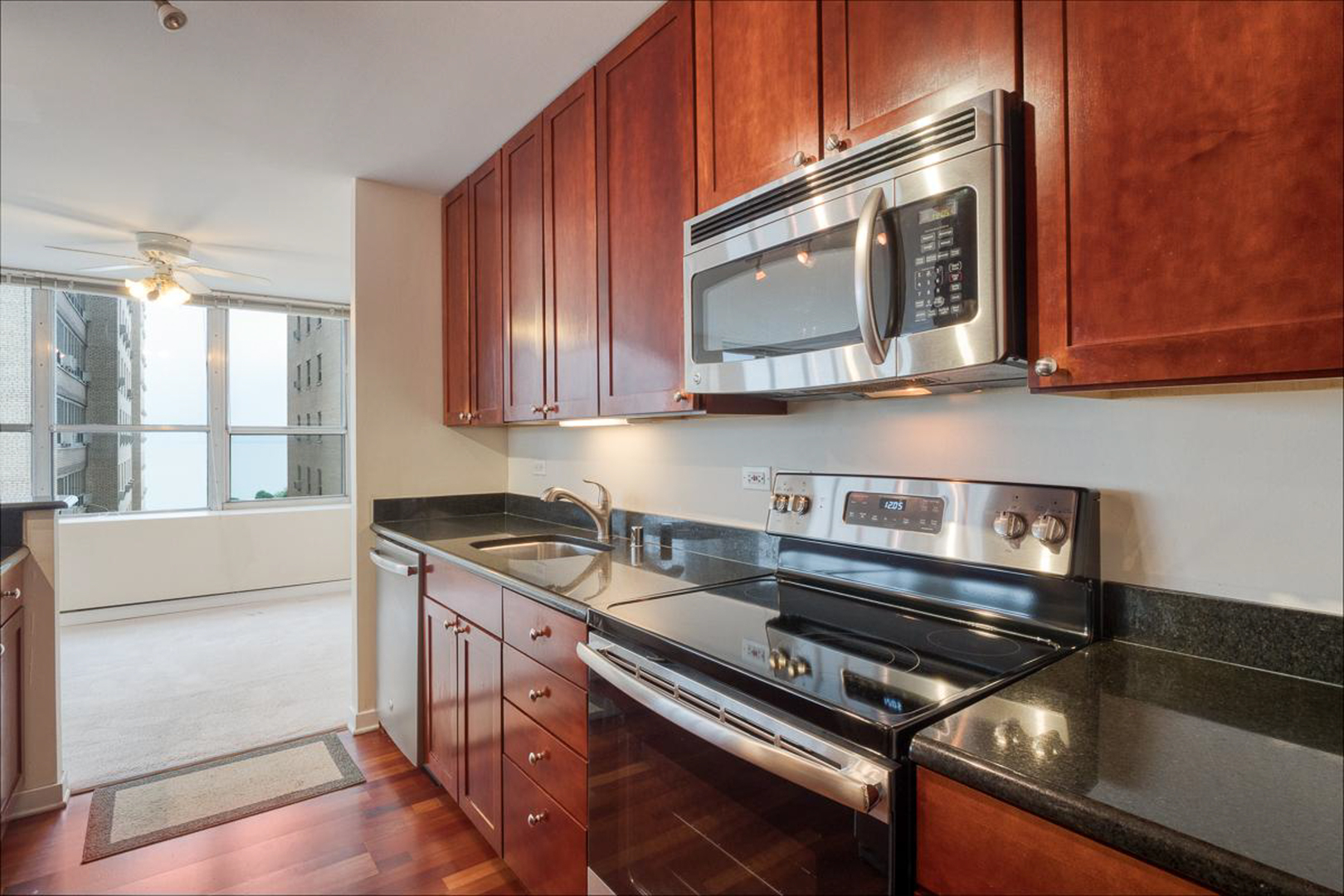 655 West Irving Park Road, Unit 1502 Chicago, IL 60613 - Photo 5 of 24 a kitchen with stainless steel appliances granite countertop a stove and a microwave