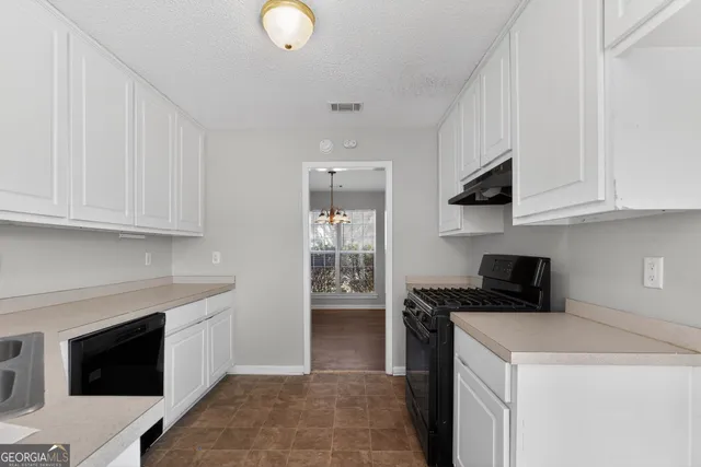 a kitchen with granite countertop a stove a sink and a white cabinets
