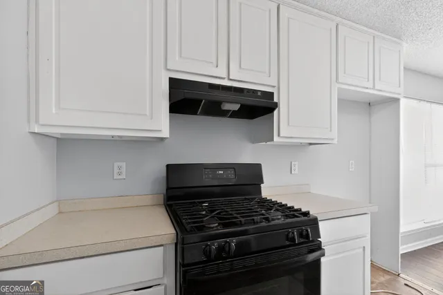 a kitchen with granite countertop white cabinets and appliances