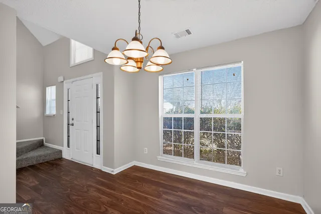 a view of a livingroom with a chandelier wooden floor and a chandelier