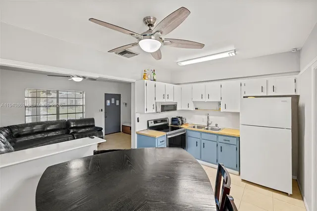 a kitchen with granite countertop a refrigerator a stove a sink dishwasher and white cabinets with wooden floor