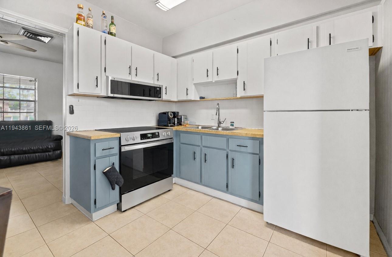 206 Southeast 5th Street Dania Beach, FL 33004 - Photo 9 of 26 a kitchen with cabinets stainless steel appliances and a refrigerator