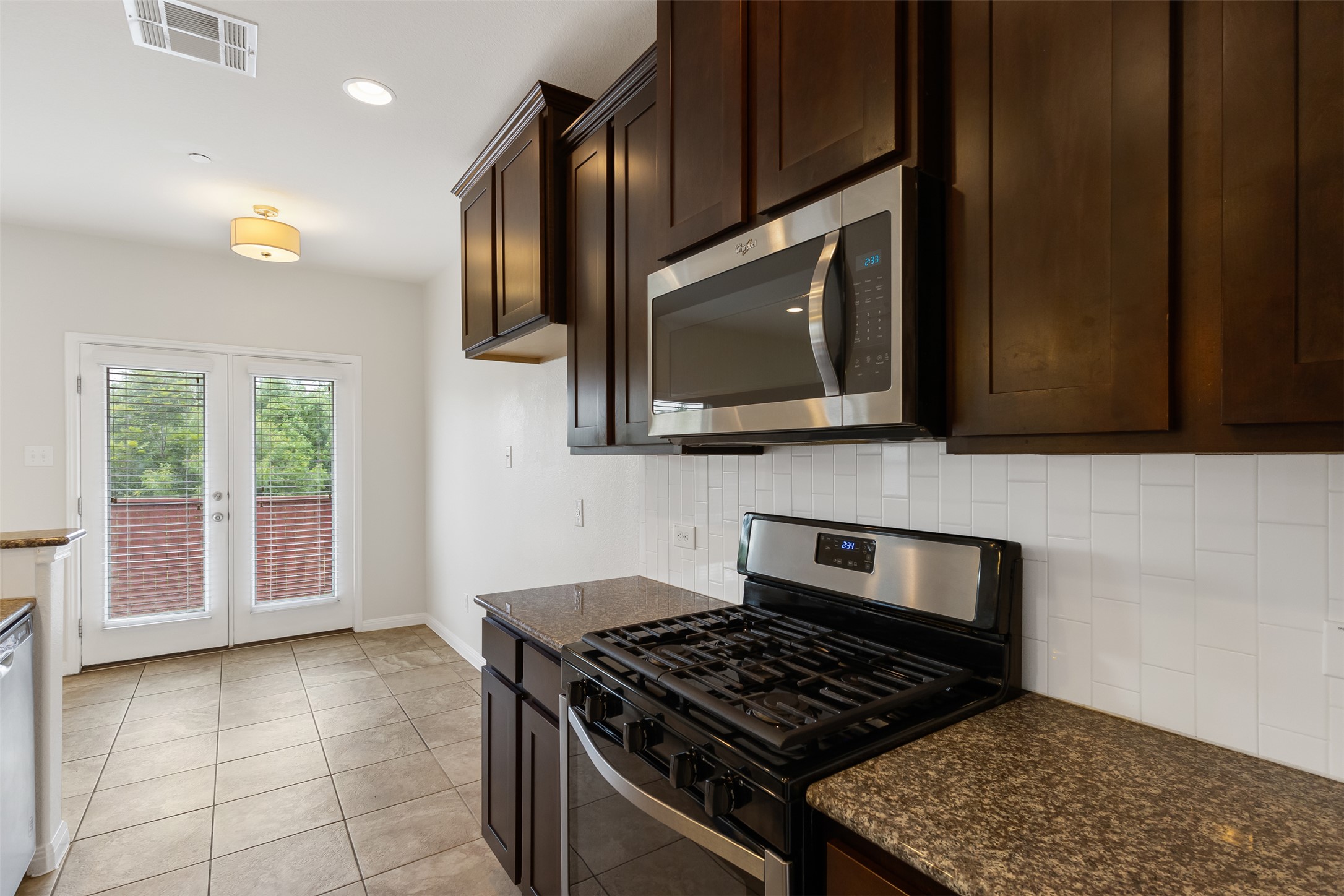 1510 Catalan Road, Unit 602 Austin, TX 78748 - Photo 12 of 36 Kitchen featuring stainless steel appliances, dark brown cabinetry, decorative backsplash, french doors, and dark stone counters