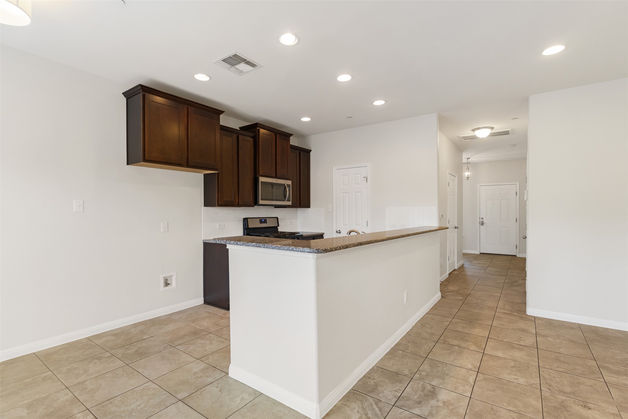 1510 Catalan Road, Unit 602 Austin, TX 78748 - Photo 9 of 36 Kitchen featuring stainless steel appliances, light tile patterned floors, recessed lighting, dark brown cabinetry, and dark stone countertops