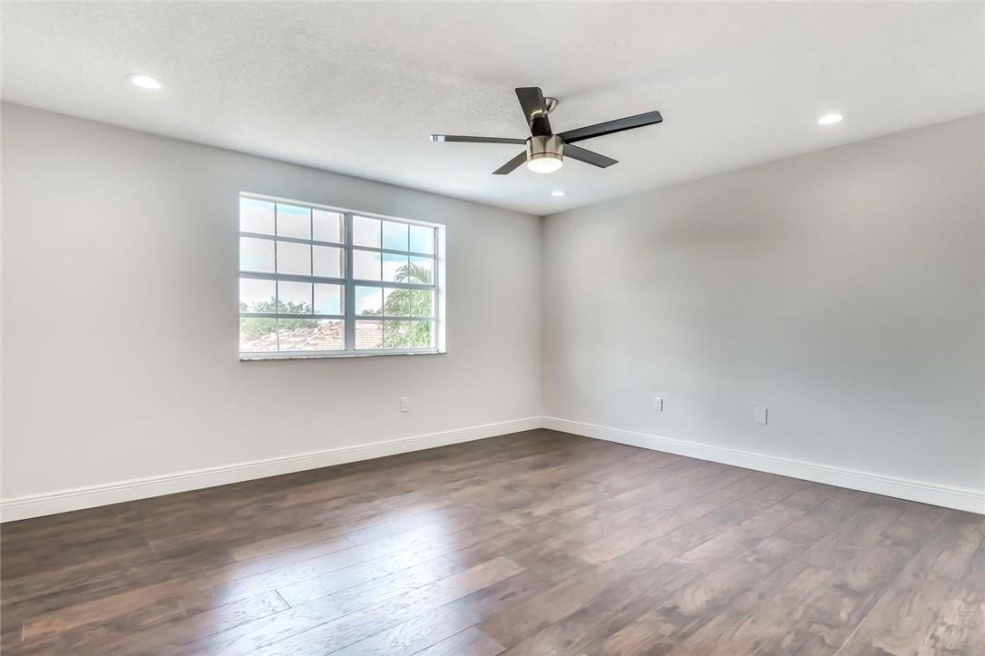 8237 Northwest 200th Terrace Hialeah, FL 33015 - Photo 14 of 30 an empty room with wooden floor fan and windows