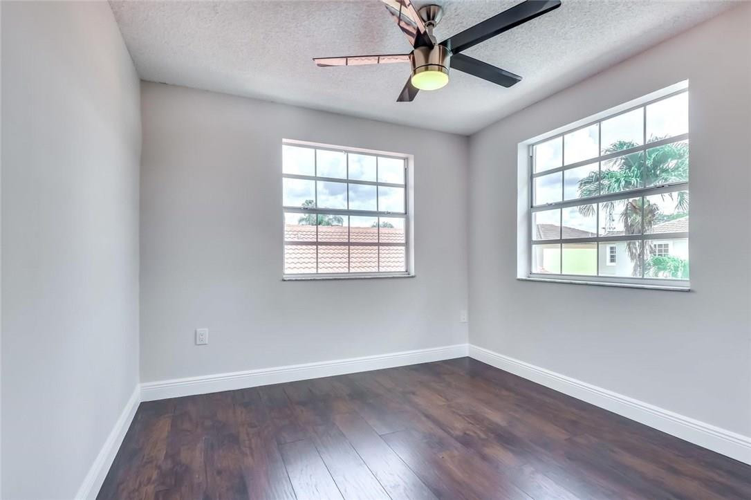 8237 Northwest 200th Terrace Hialeah, FL 33015 - Photo 21 of 30 an empty room with wooden floor ceiling fan and windows
