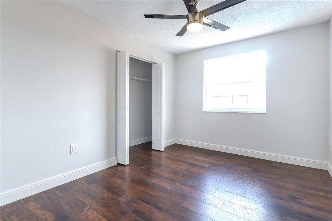 8237 Northwest 200th Terrace Hialeah, FL 33015 - Photo 22 of 30 an empty room with wooden floor ceiling fan and windows