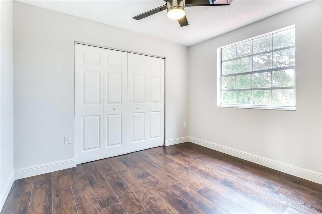 8237 Northwest 200th Terrace Hialeah, FL 33015 - Photo 25 of 30 an empty room with wooden floor chandelier fan and windows