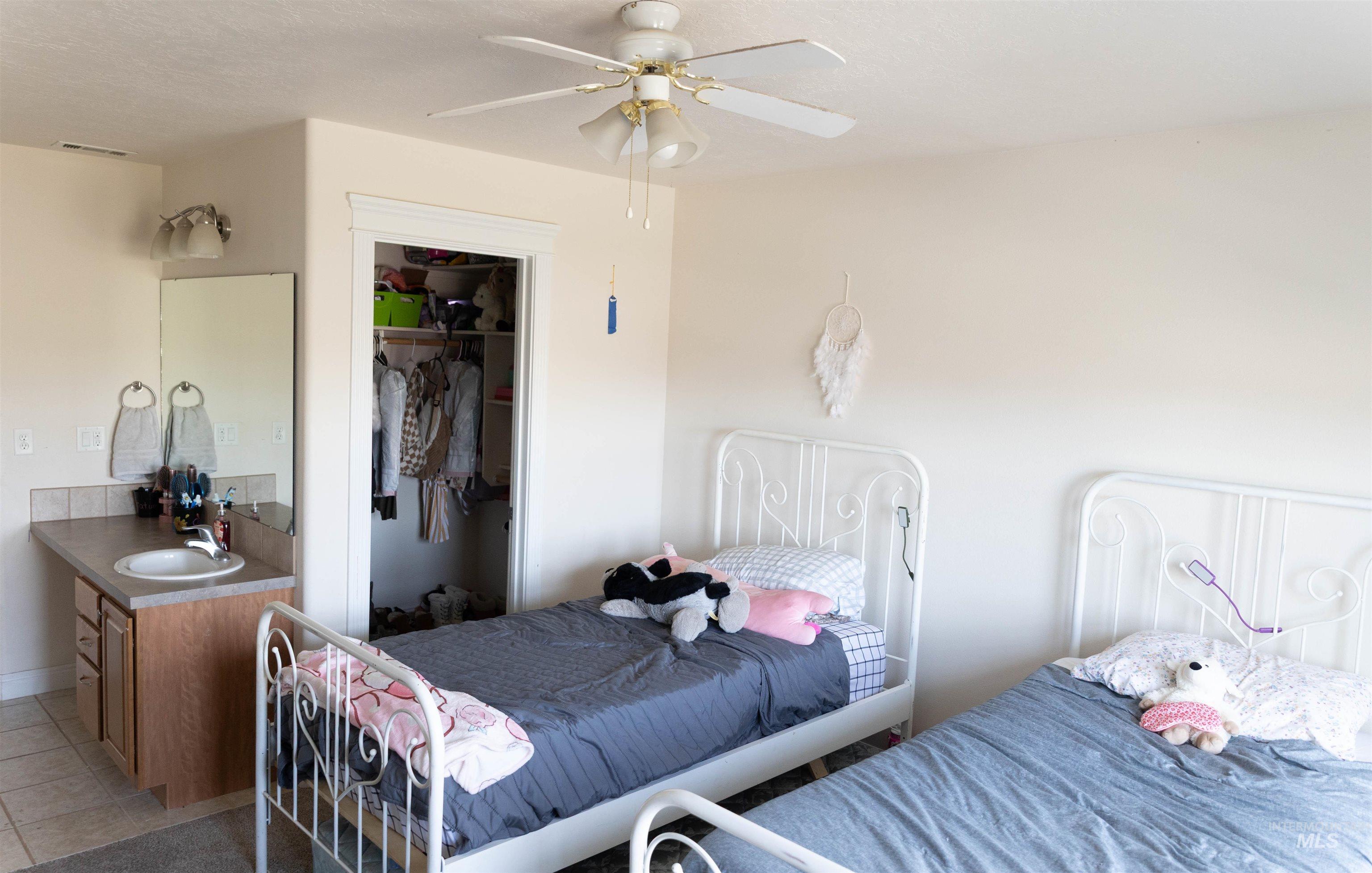 765 Southwest Foley Street Mountain Home, ID 83647 - Photo 12 of 37 Bedroom featuring a closet, light tile patterned floors, and a ceiling fan