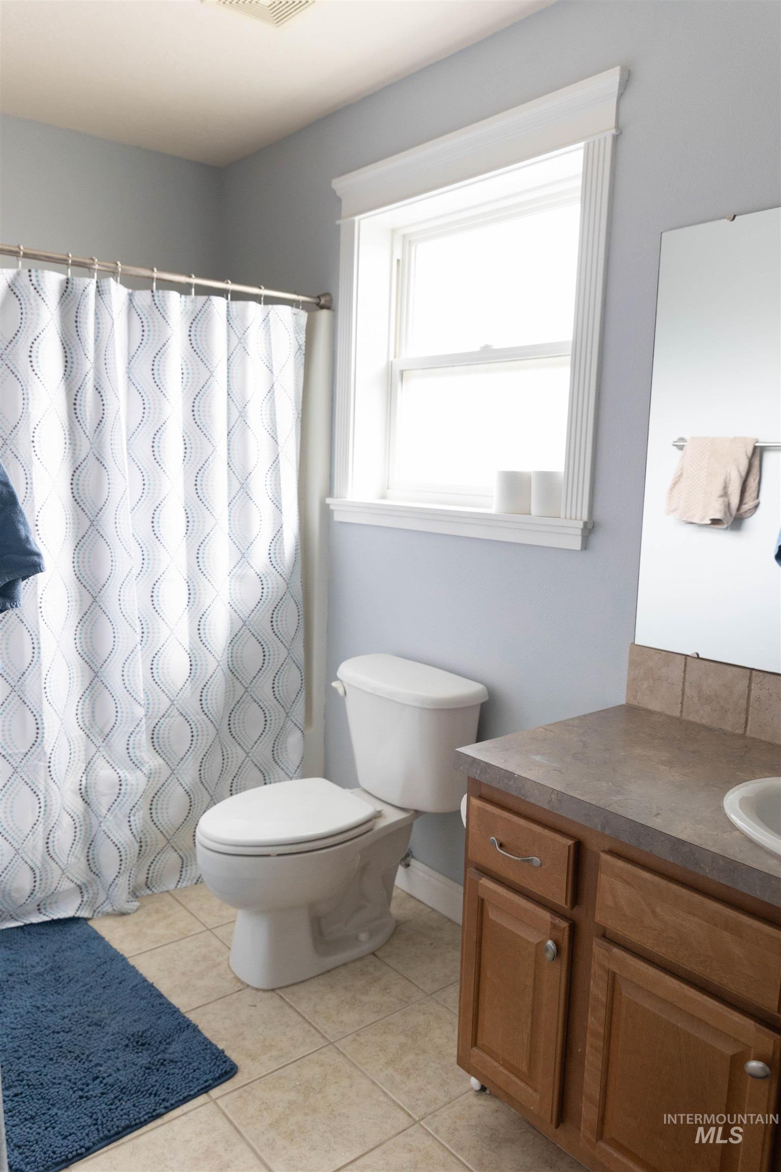 765 Southwest Foley Street Mountain Home, ID 83647 - Photo 18 of 37 Bathroom featuring curtained shower, vanity, and light tile patterned floors