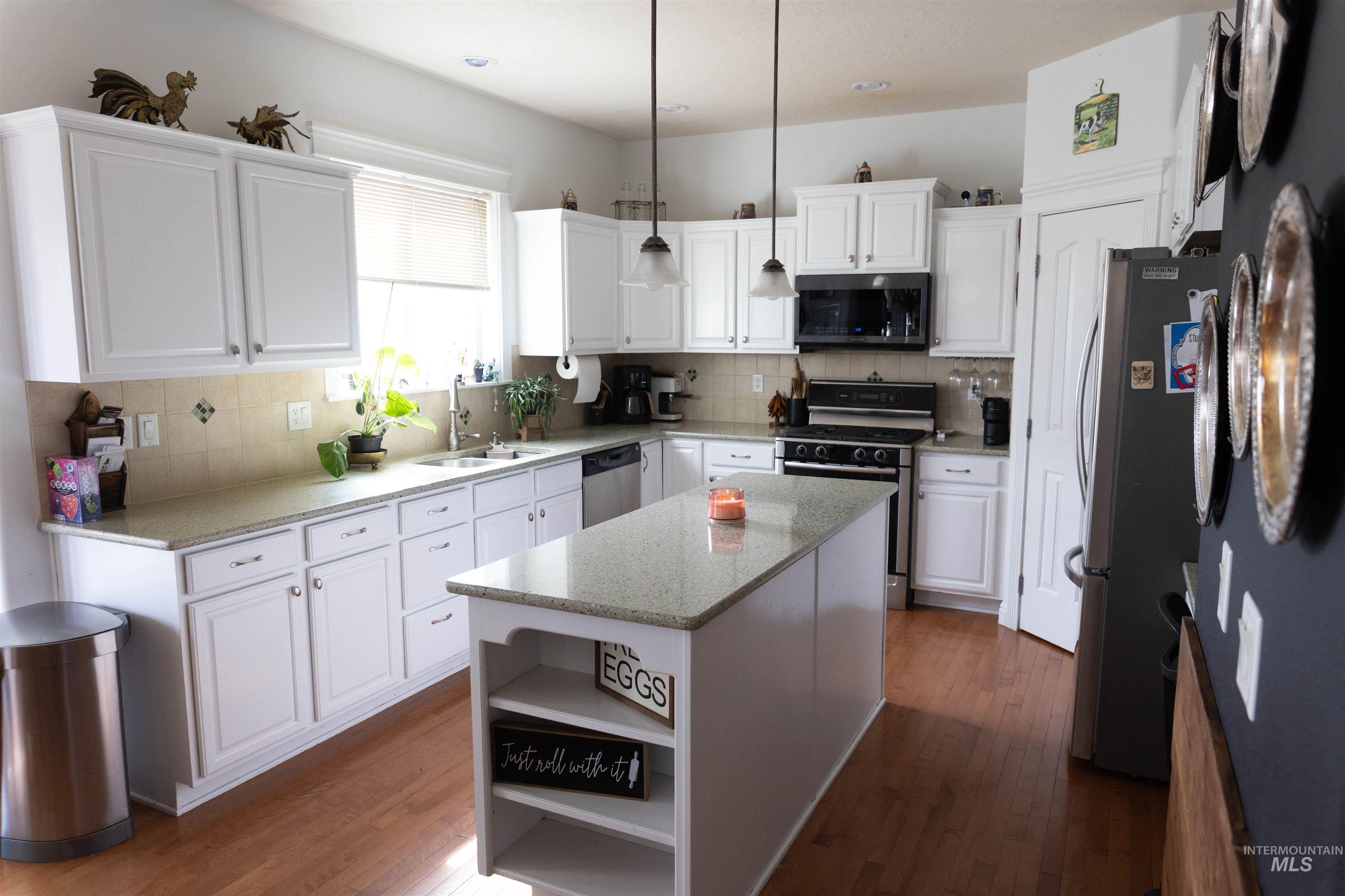 765 Southwest Foley Street Mountain Home, ID 83647 - Photo 3 of 37 Kitchen with a center island, open shelves, white cabinets, dark wood finished floors, and stainless steel appliances