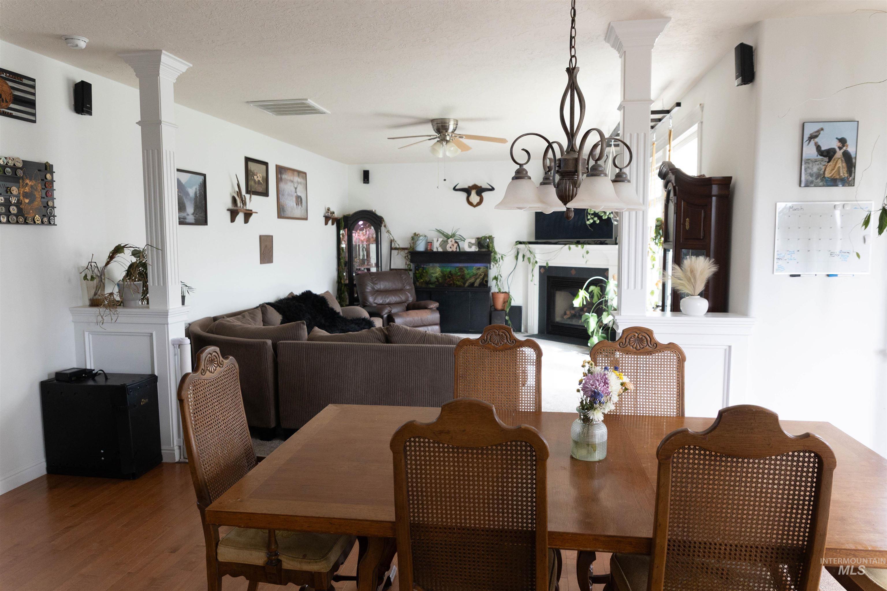 765 Southwest Foley Street Mountain Home, ID 83647 - Photo 5 of 37 Dining room with a fireplace, ceiling fan, wood finished floors, and suspended lighting