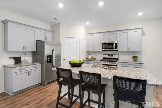 a kitchen with stainless steel appliances a stove a sink a table and chairs
