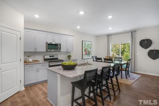a kitchen with a table chairs microwave and cabinets