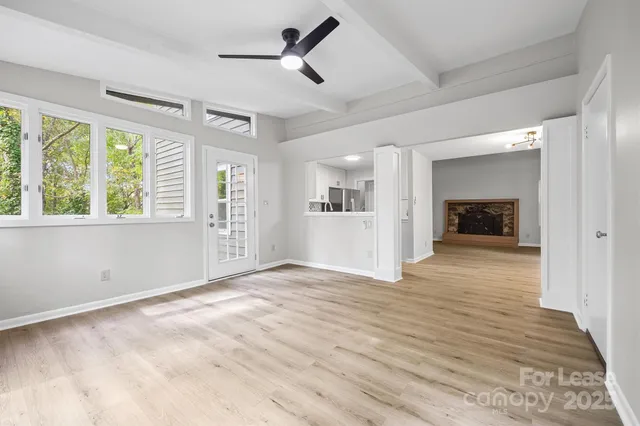 a view of an empty room with a window and a kitchen