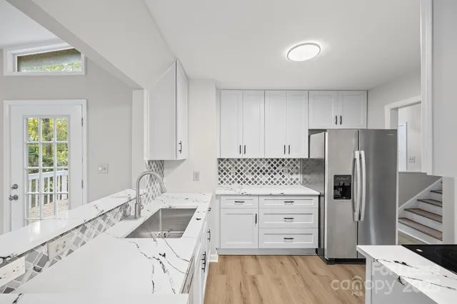 a kitchen with a stove a refrigerator and a sink with wooden floor