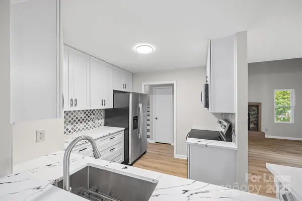 a kitchen with stainless steel appliances a sink a stove a refrigerator cabinets and a dining table