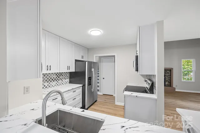 a kitchen with stainless steel appliances a sink a stove a refrigerator cabinets and a dining table