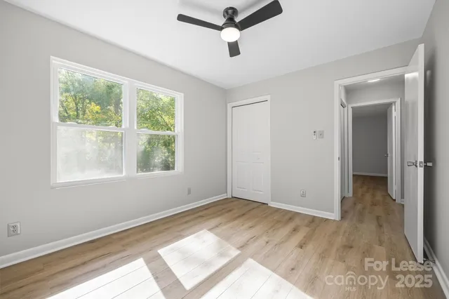 a view of empty room with wooden floor and fan