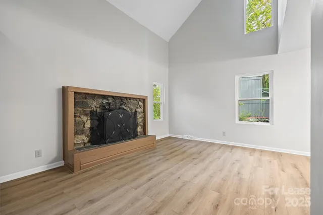 a view of an empty room with window and wooden floor