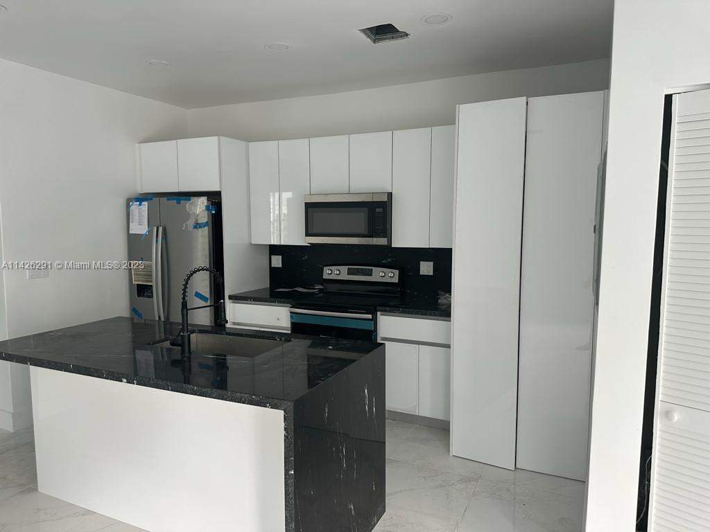 437 Northeast 70th Street Miami, FL 33138 - Photo 1 of 1 a kitchen with granite countertop a refrigerator and a stove top oven