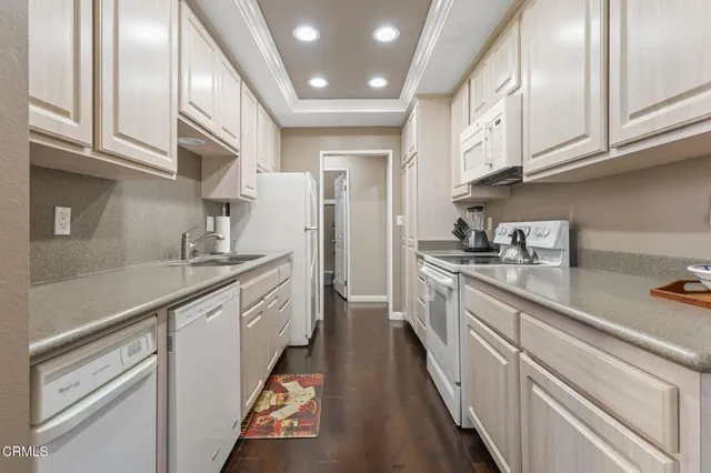a kitchen with granite countertop white cabinets and white appliances