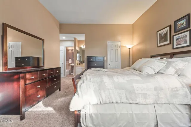 a large bedroom with a bed and a mirror on dresser