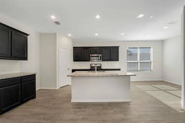a kitchen with stainless steel appliances granite countertop a stove a sink and a microwave