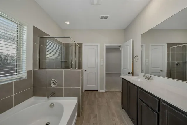 a bathroom with a tub a sink and mirror