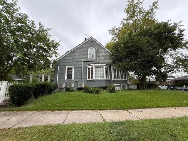 a front view of a house with a yard and trees