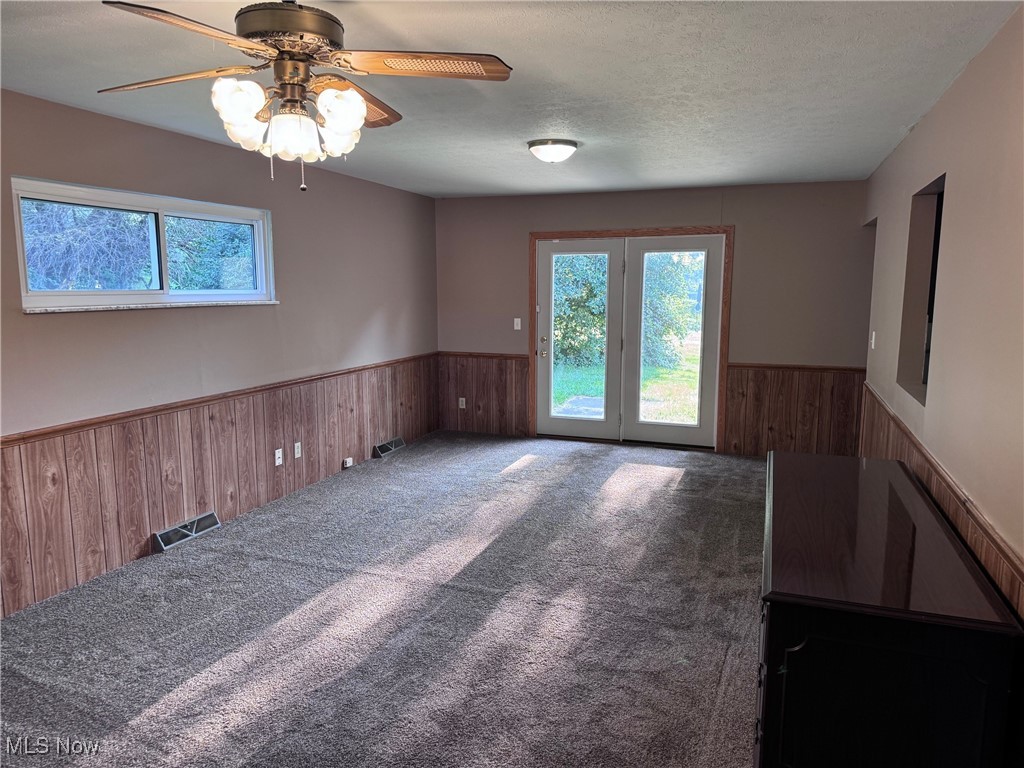 1719 Beryl Road Akron, OH 44312 - Photo 10 of 27 Empty room featuring ceiling fan, french doors, a textured ceiling, and carpet flooring