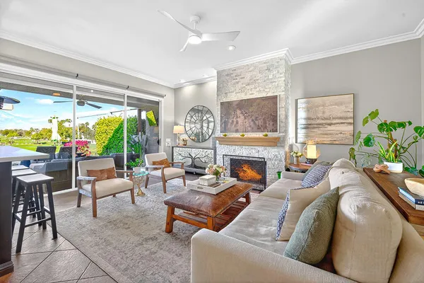 a living room with furniture a fireplace and a floor to ceiling window