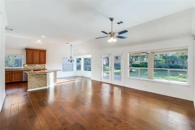 a view of a kitchen with furniture a ceiling fan and wooden floor