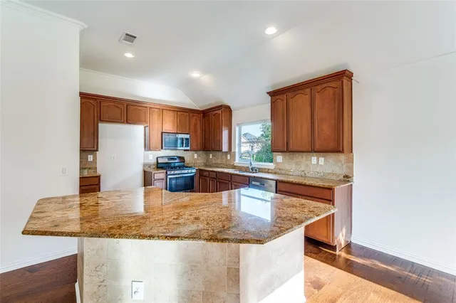 a kitchen with granite countertop a sink a counter top space and cabinets