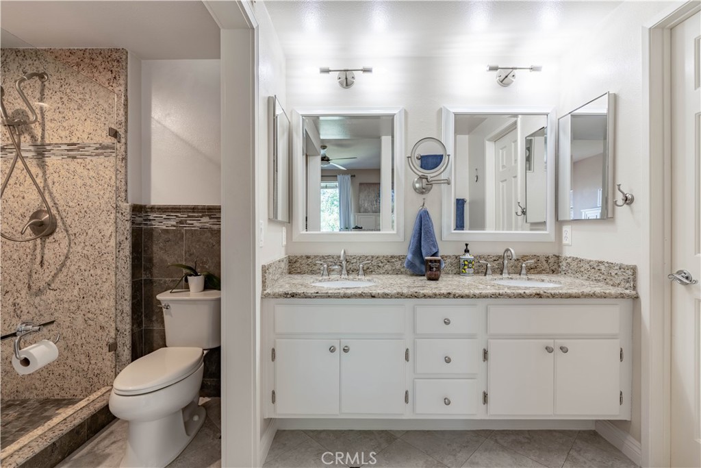 a bathroom with a granite countertop sink toilet a mirror a vanity and shower