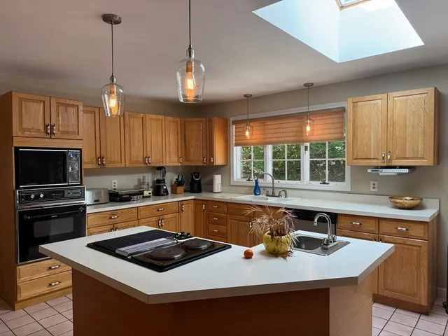 a kitchen with a stove a sink a center island and windows
