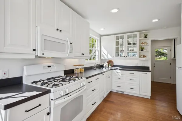 a kitchen with granite countertop white cabinets and appliances