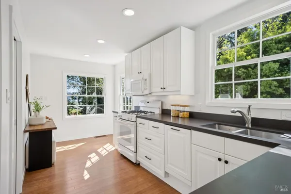 a kitchen with granite countertop a stove a sink and a granite counter tops with white cabinets