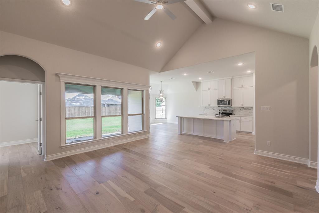 609 Keel Way Azle, TX 76020 - Photo 13 of 32 a view of an empty room with wooden floor and a kitchen