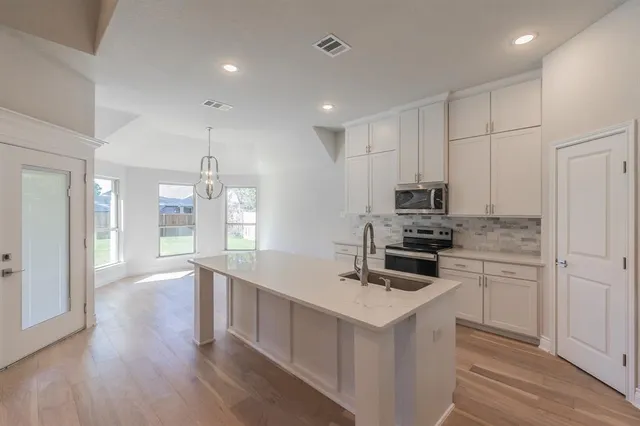 a kitchen with a sink a stove a refrigerator and white cabinets