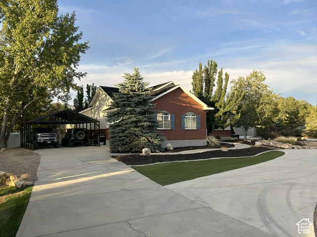 1750 West 4100 North Helper, UT 84526 - Photo 2 of 50 Brick and siding exterior with arched windows, concrete driveway, attached carport, mature evergreen landscaping, and artificial turf accents