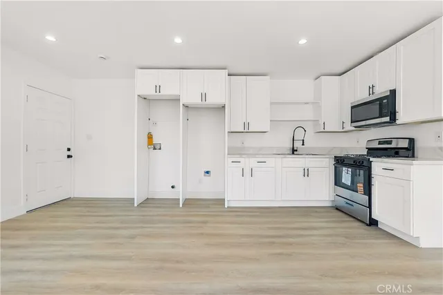 a kitchen with stainless steel appliances kitchen island granite countertop a sink a stove a refrigerator and white cabinets