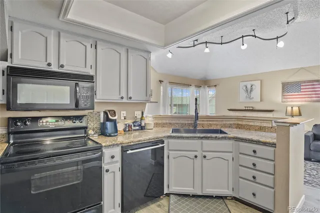 a kitchen with granite countertop white cabinets and white appliances