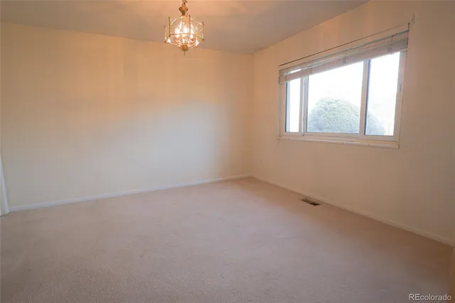 en empty room with windows and chandelier