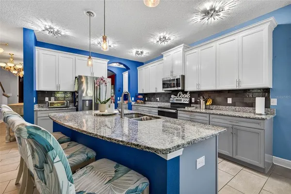 a kitchen with kitchen island granite countertop a sink cabinets and stainless steel appliances