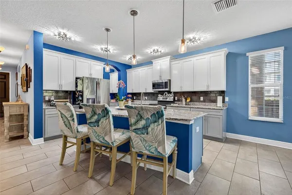 a kitchen with stainless steel appliances granite countertop a stove a sink a refrigerator a microwave oven with a dining table and chairs